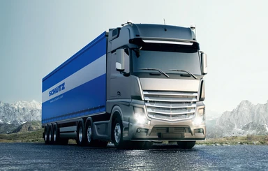 Moderner Lkw mit blauem Auflieger auf einer Straße in Berglandschaft, steht für schnellen und zuverlässigen Transport